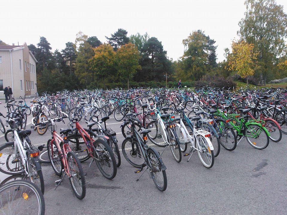 Kuvassa on paljon polkupyöriä pyörätelineissä koulupihalla.