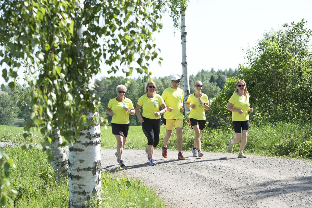 Viiden hengen lenkkiporukka juoksee hiekkatietä kesäpäivänä.