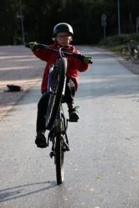Poika keulii pyörällä kuvajaa kohti kypärä päässä.