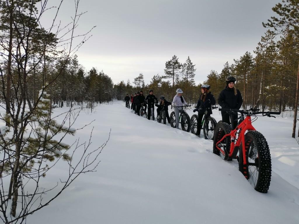 Yläkoulun oppilaat ajavat jonossa lumihangessa FatBikeillä.